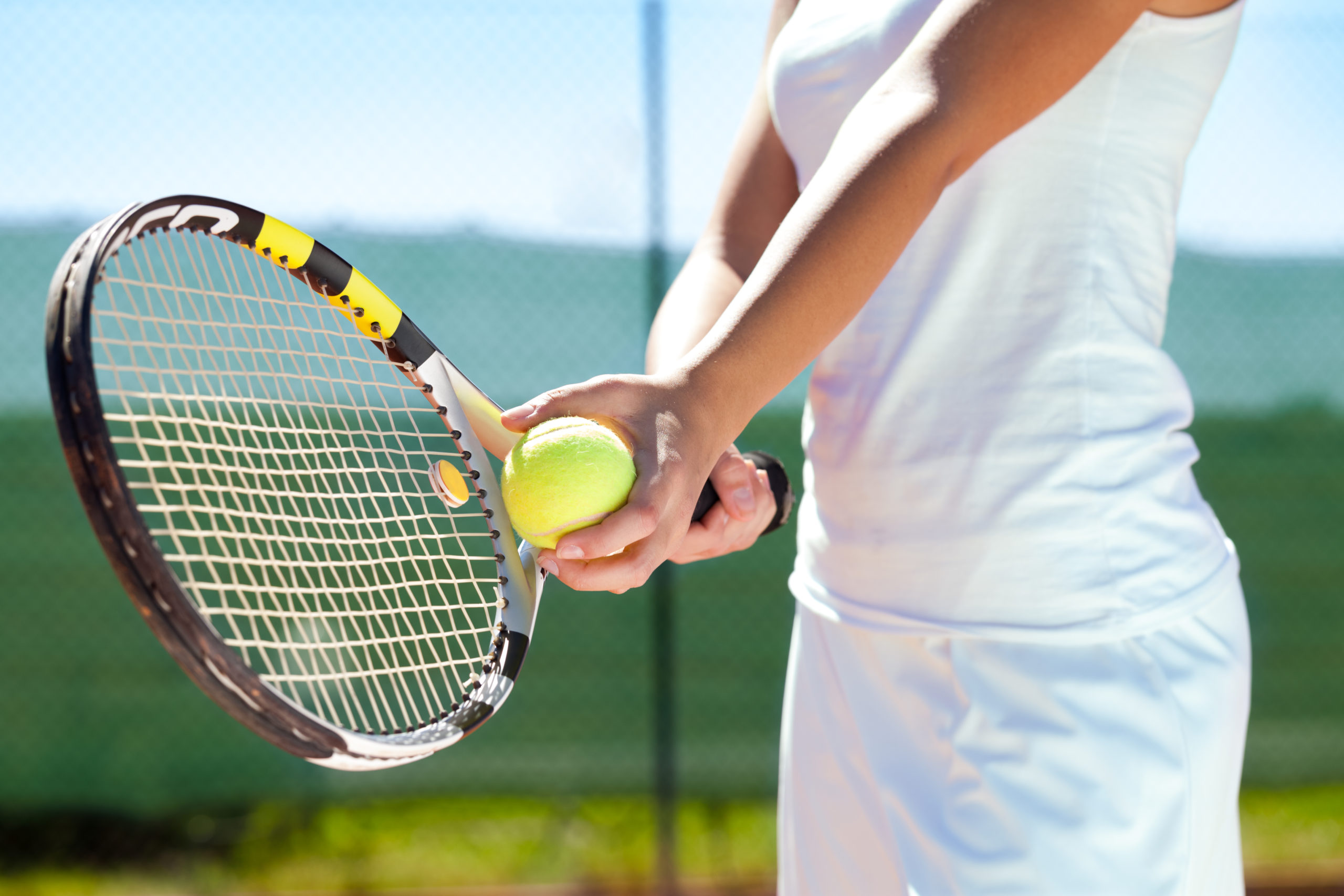 Player's hand with tennis ball and racket